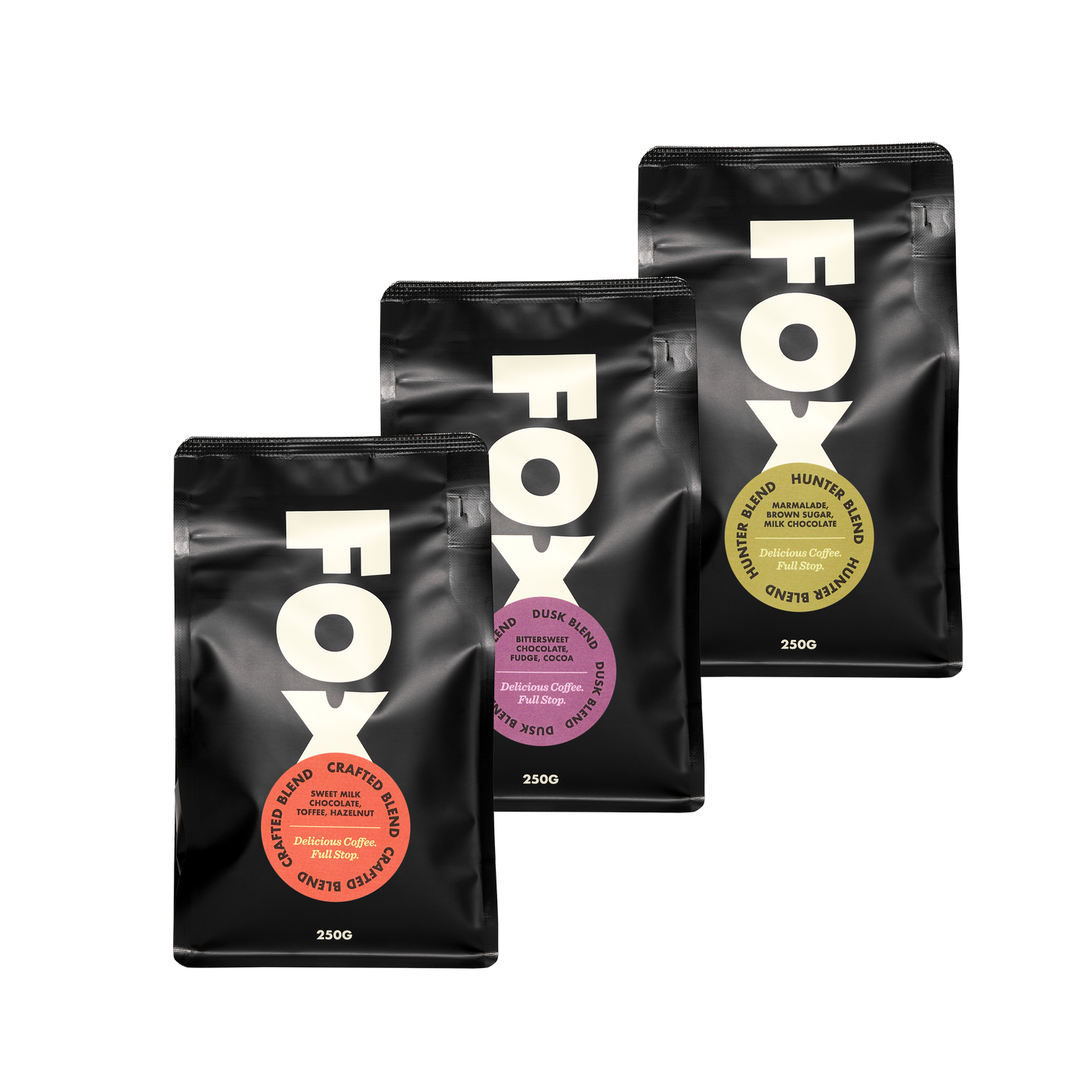 Three sealed pouches of FOX brand coffee, each labeled with a different color and blend name, arranged diagonally against a white background.